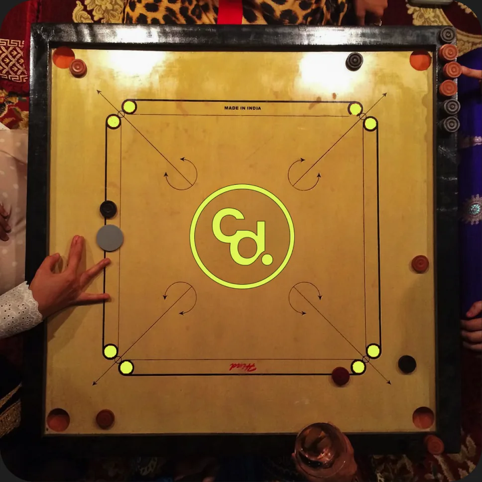 A carrom board with the Cd mark in the centre circle.